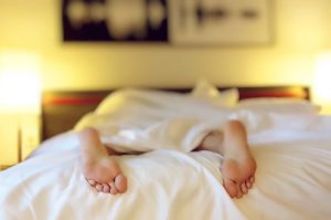 Eine Person im Bett in Bettwäsche, die Füße sind zusehen.