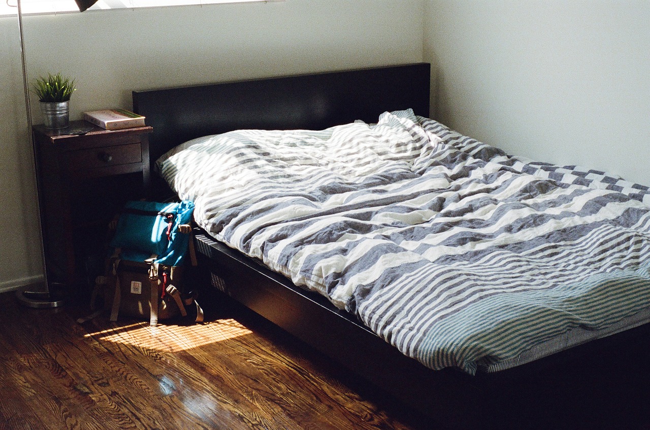 In einem Zimmer steht ein mit Bettwäsche bezogenes Bett